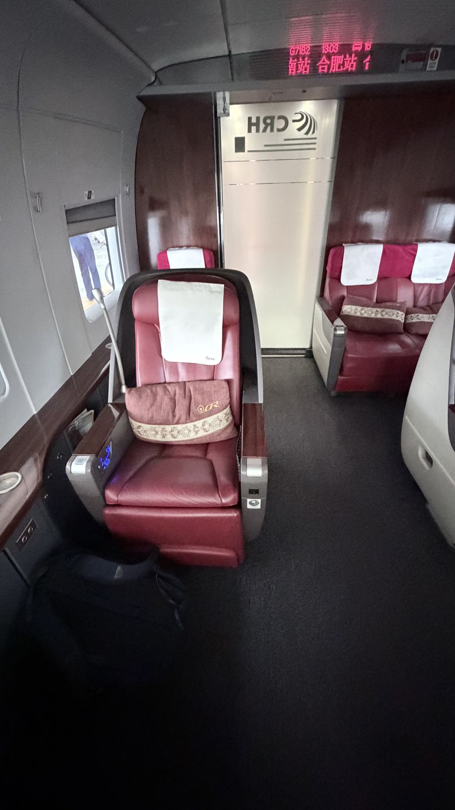 A wide red leather business-class seat in the small front cabin of a CRH high-speed train